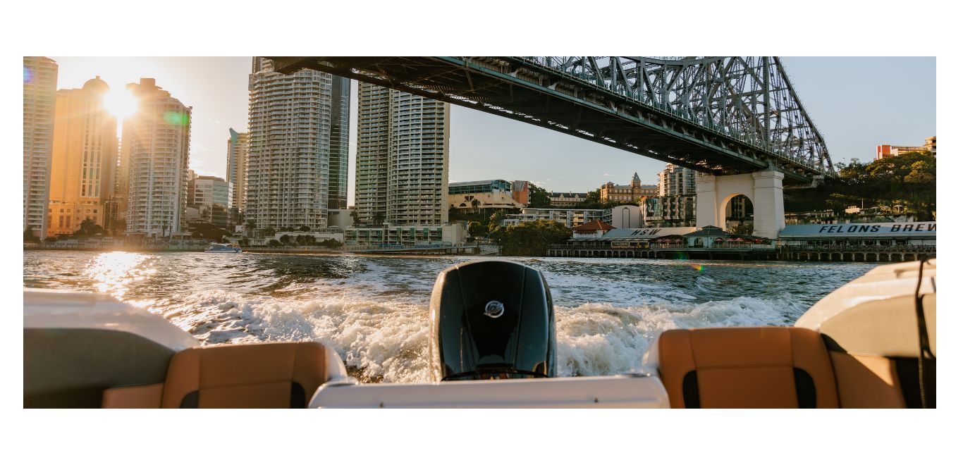 A view from a Freedom boat cruising beneath Brisbane Story Bridge at sunset