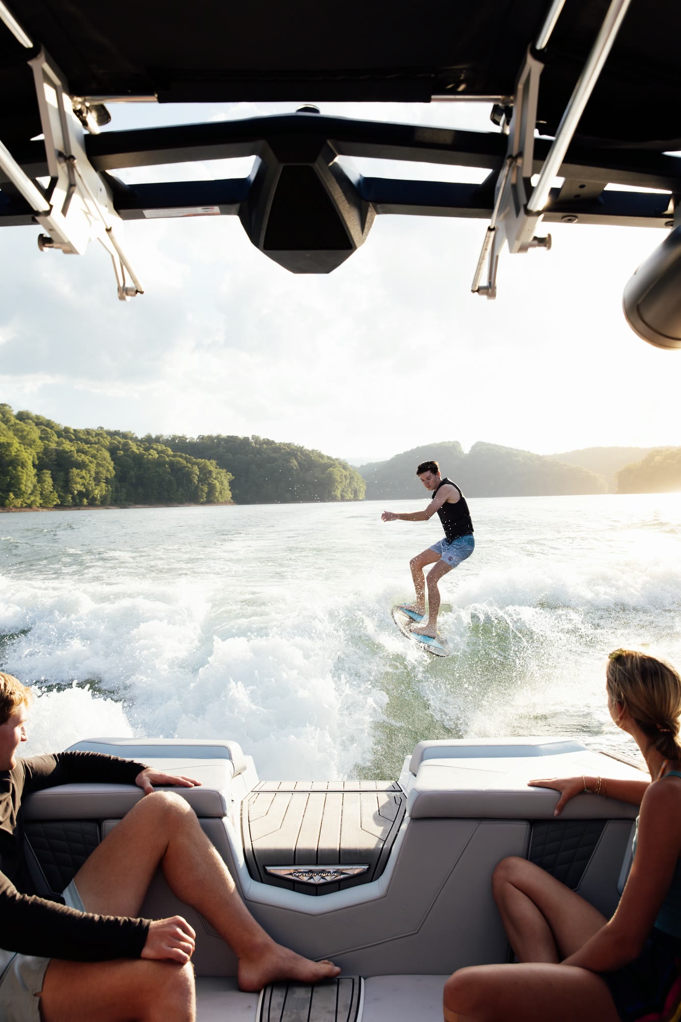 A wakesurfer seen from the rear of the tow boat at sunset