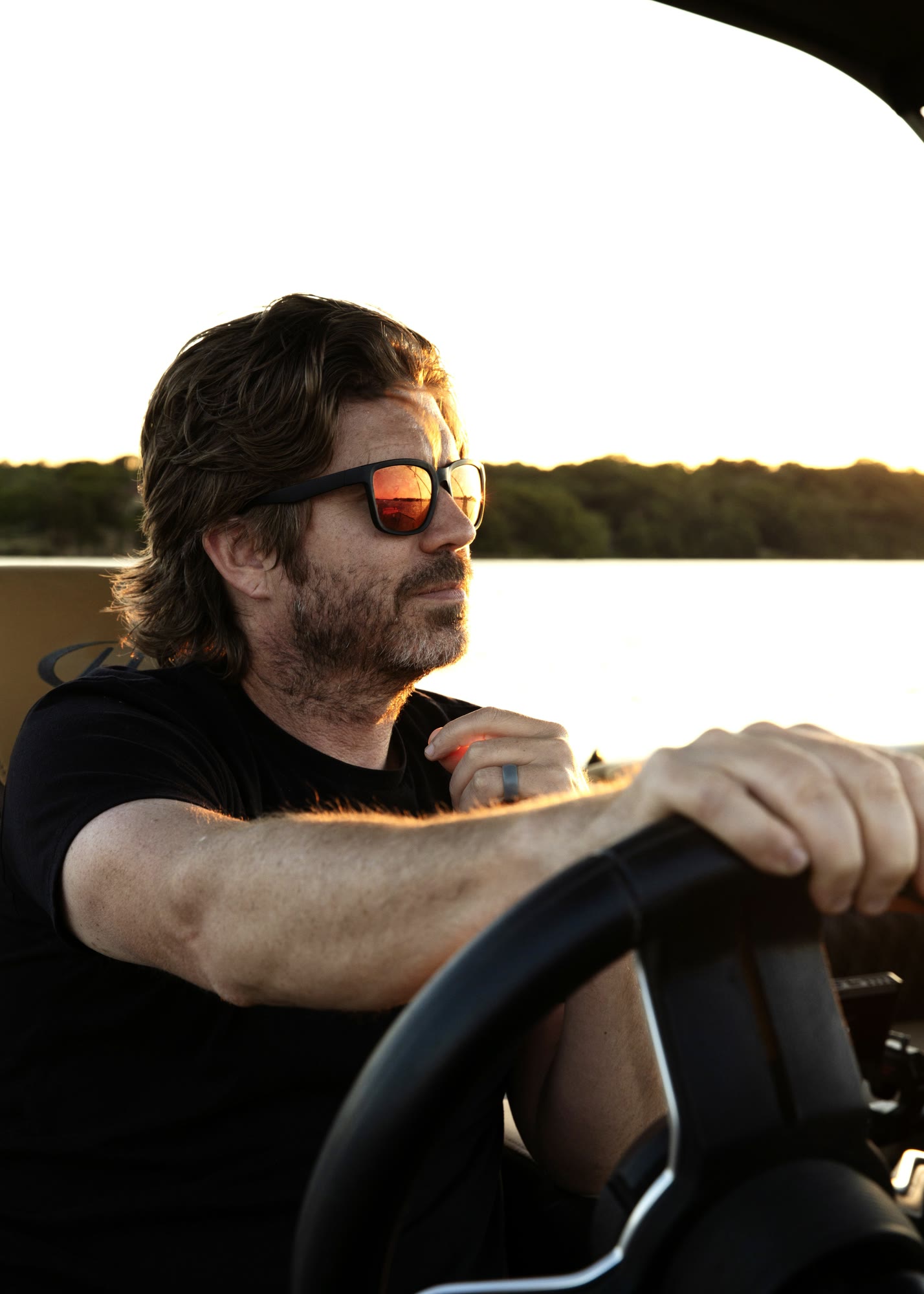 A person steering a boat at the helm as evening light settles on the water