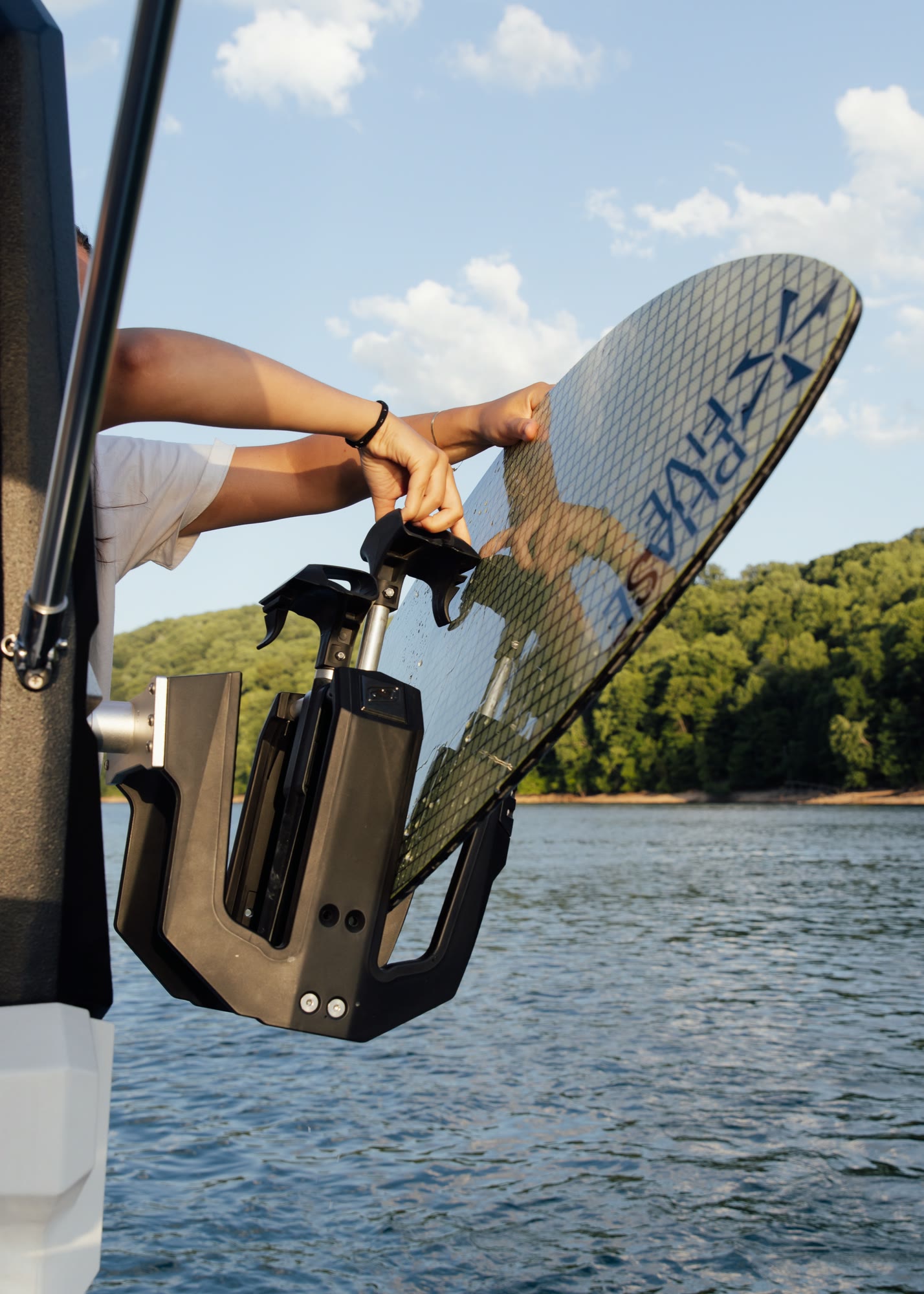 A hand placing a wakesurf board into a boat board rack