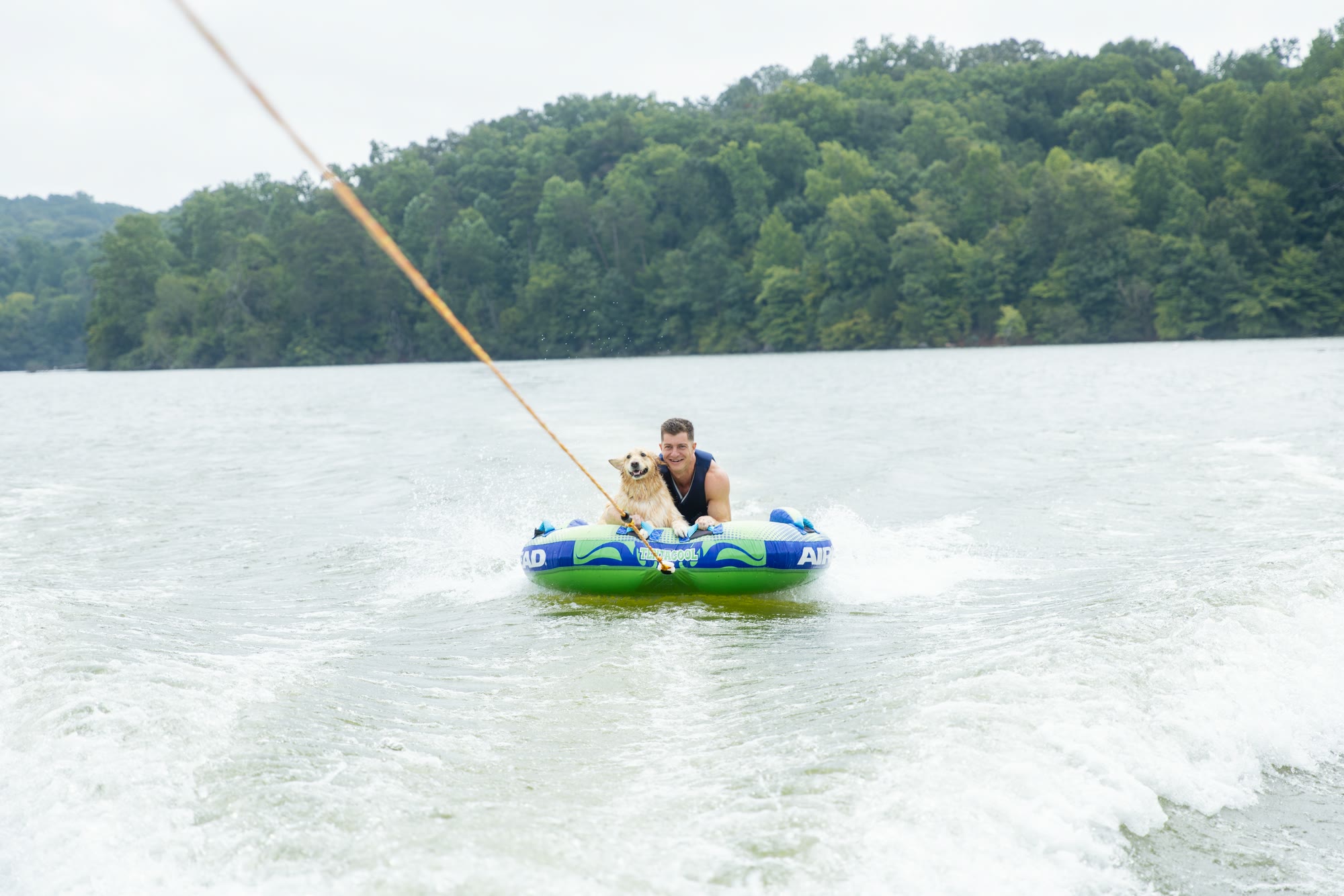 A golden retriever and guest on a towable tube on the lake