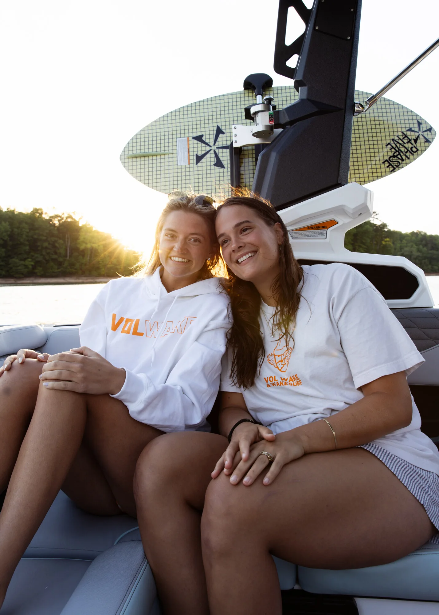 Two Vol Wake friends smiling together aboard a Nautique on Norris Lake at sunset