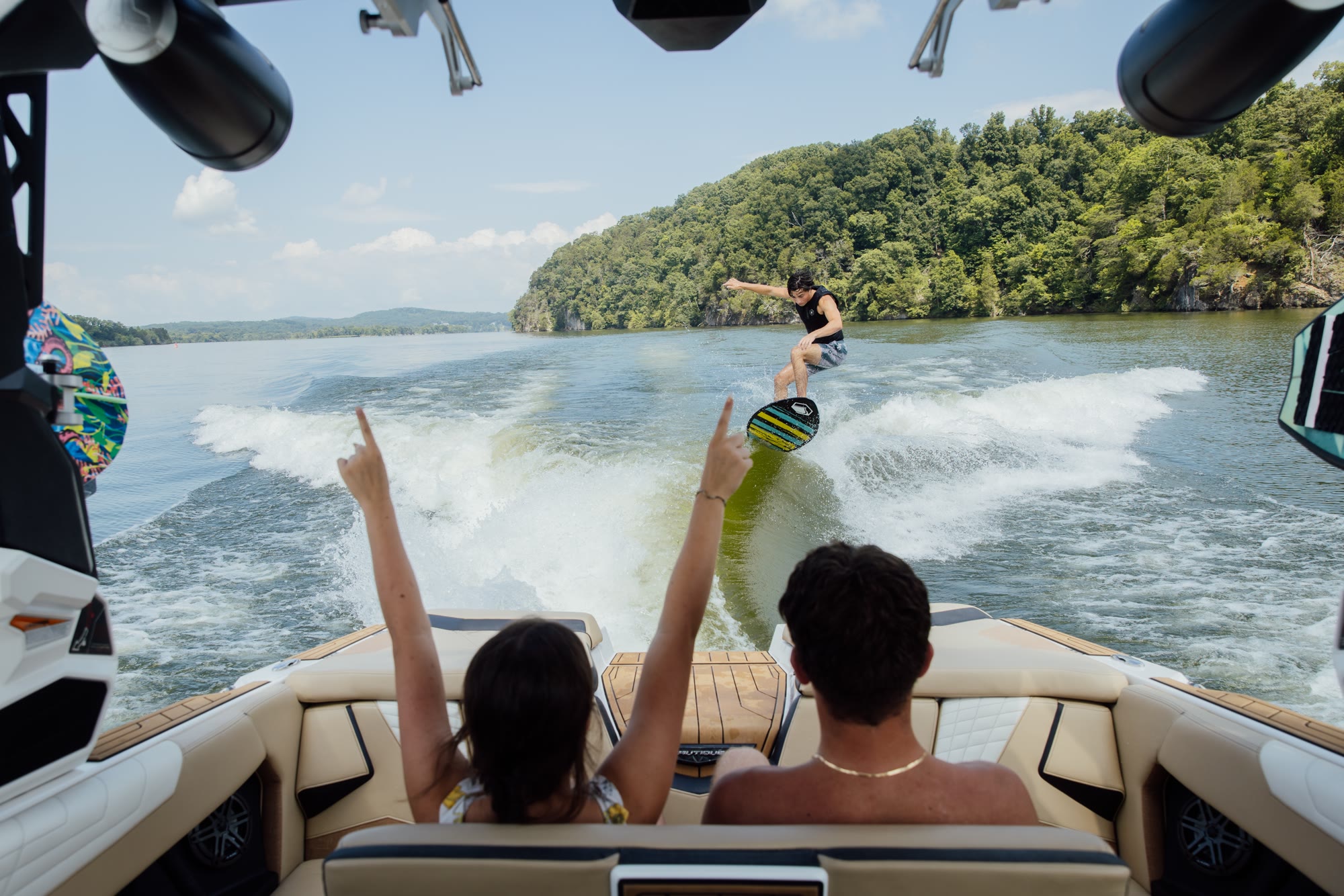 Passengers watching a wakesurfer from the seating of a boat under way