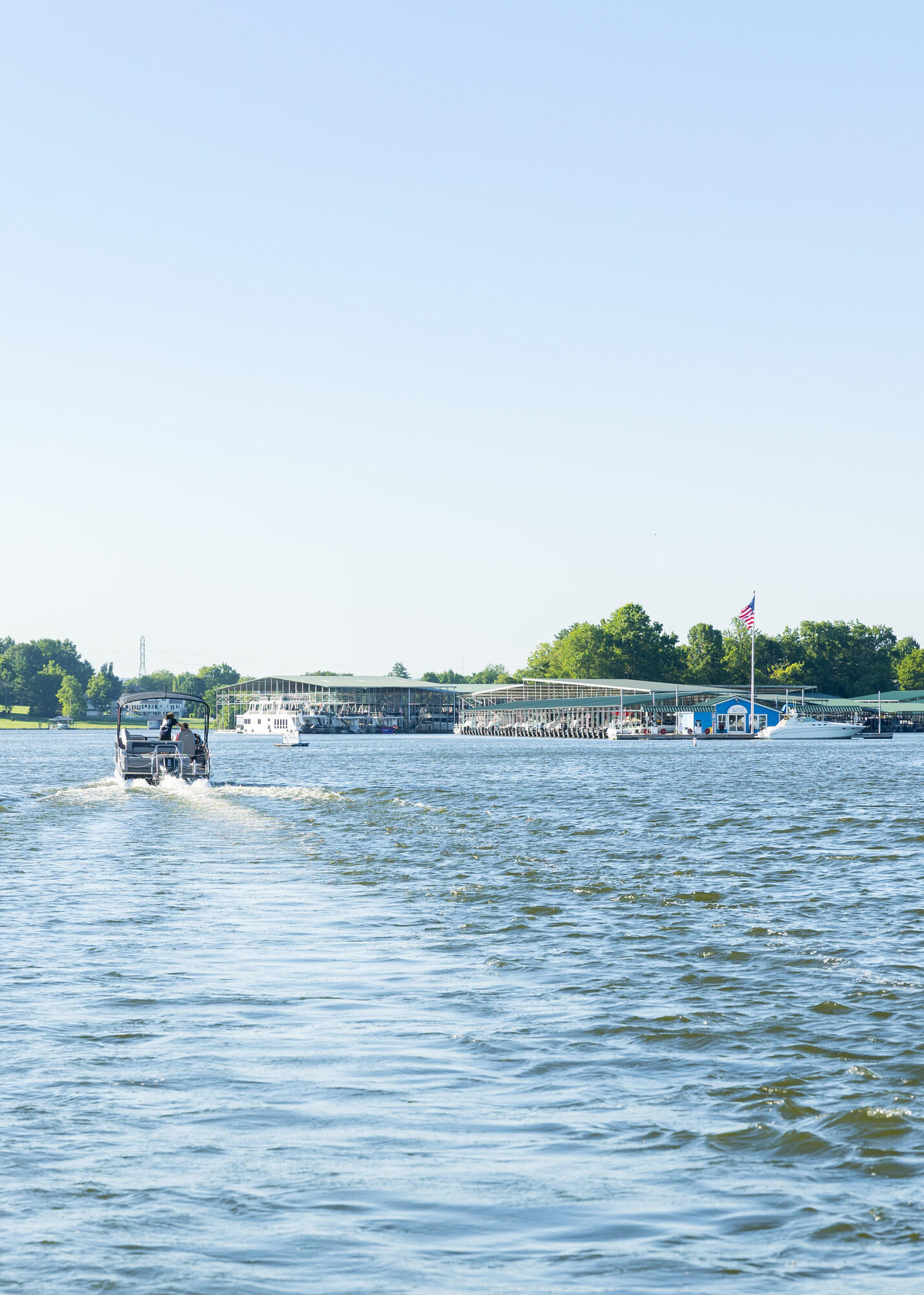 A boat approaching Gallatin Marina beside its landmark American flag on Old Hickory Lake