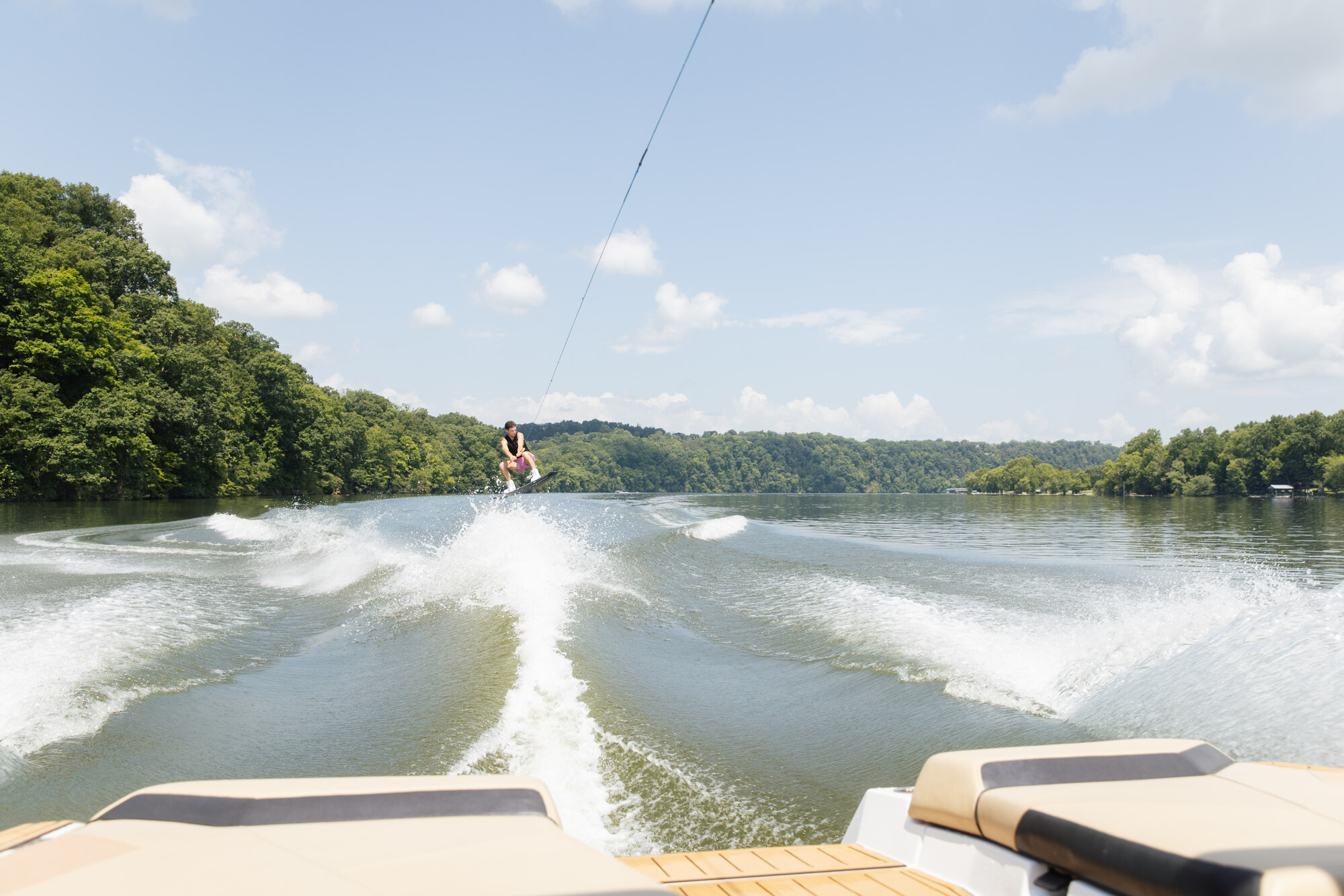 An airborne wakeboarder holding the tow rope behind a boat