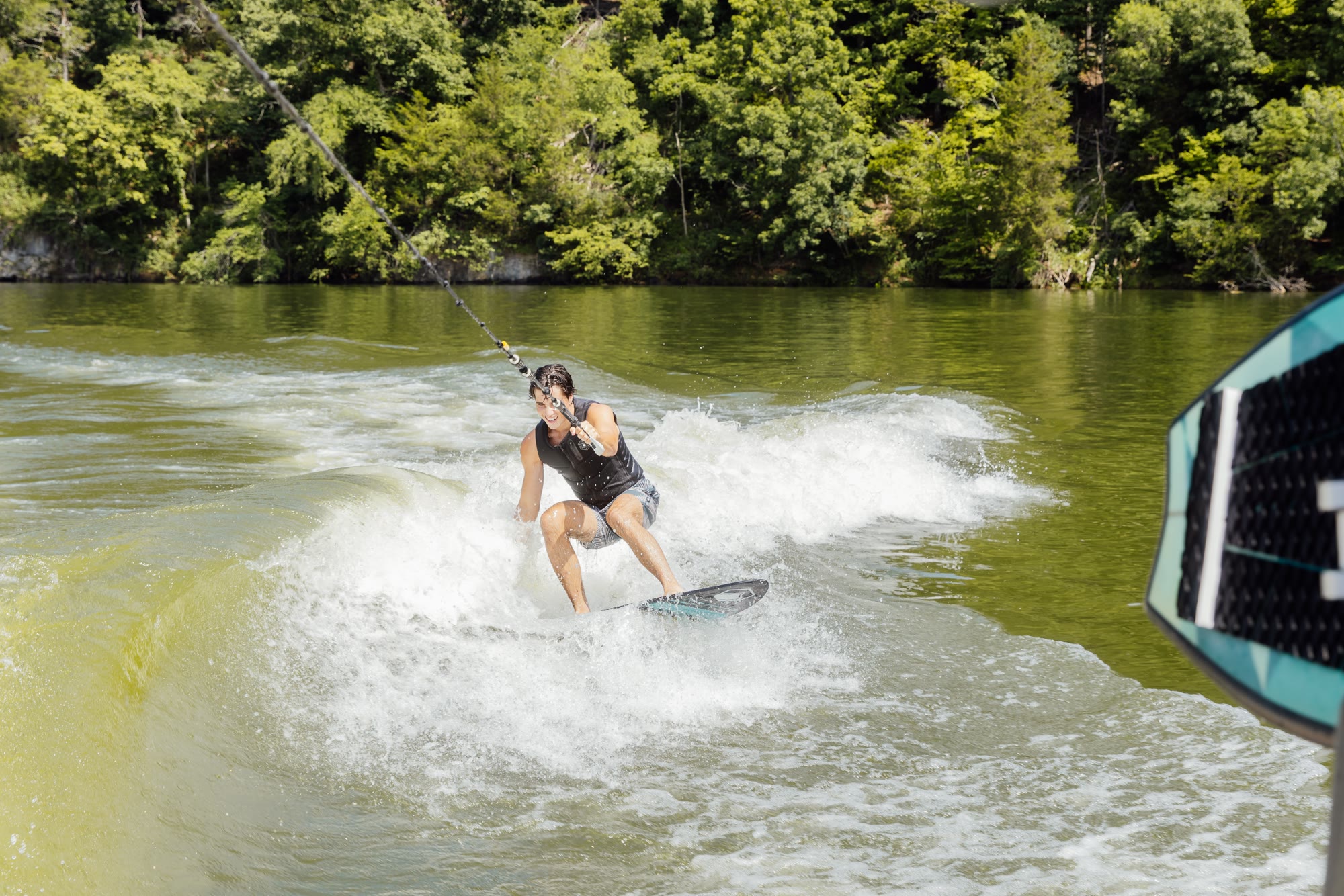 A wakesurfer riding the wake behind a club boat