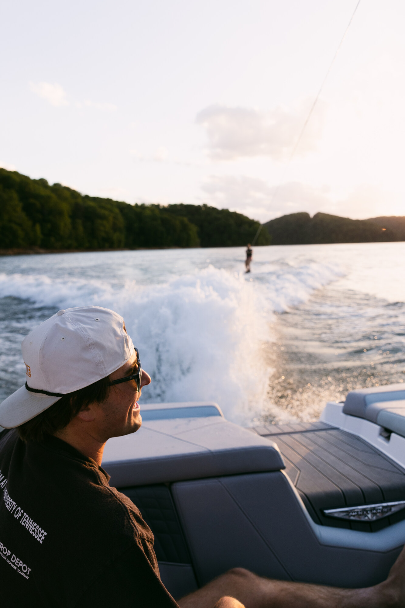 Guests watching a young wakesurfer behind the boat in golden light